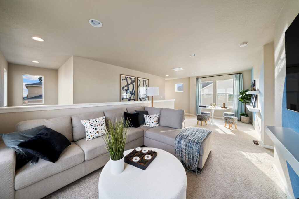 Spacious loft living area with sectional sofa, round tables, and bright windowed seating nook.