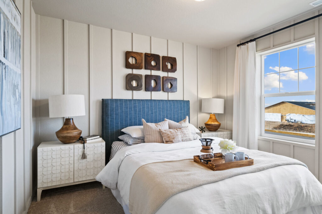 Neutral-toned bedroom with vertical paneled wall, blue upholstered headboard and tray on bed.