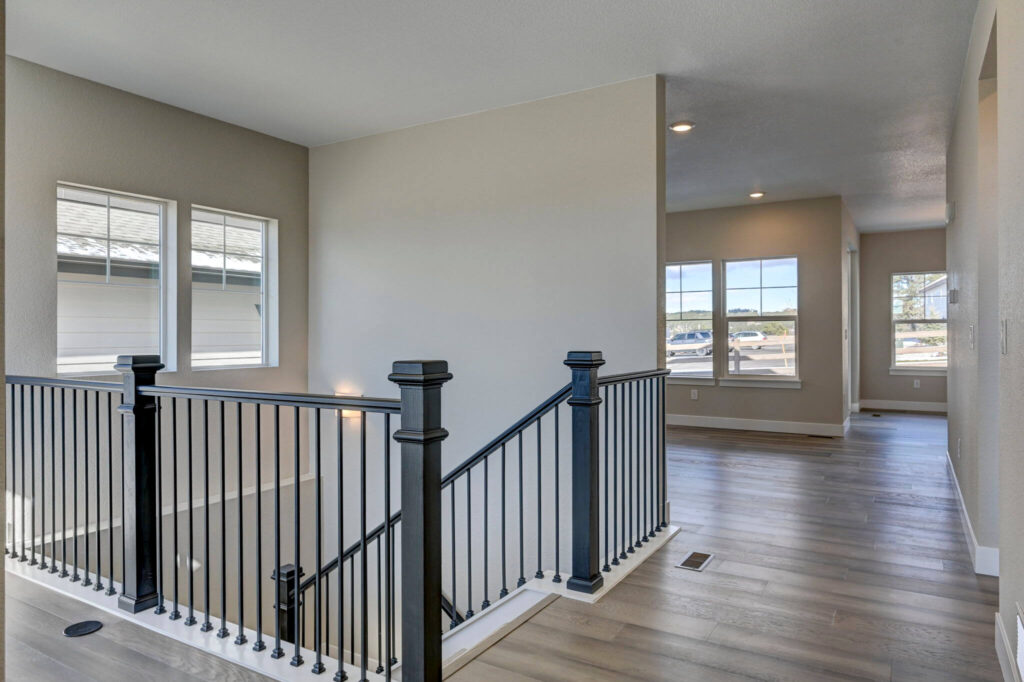 Interior upper landing with black metal railing overlooking a stairwell and open hallway.