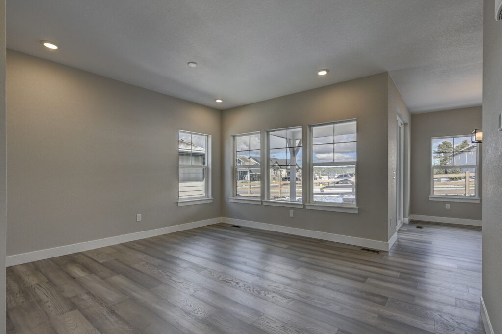 Bright open living area with wood-look flooring and multiple front-facing windows.