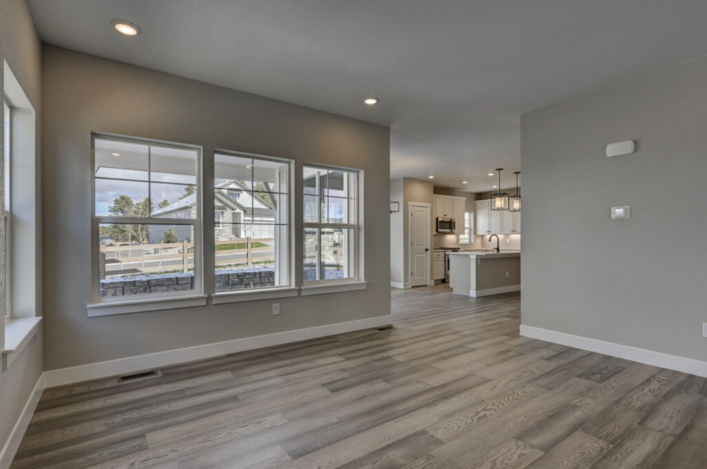 Bright room with three front-facing windows and view into an open kitchen area.