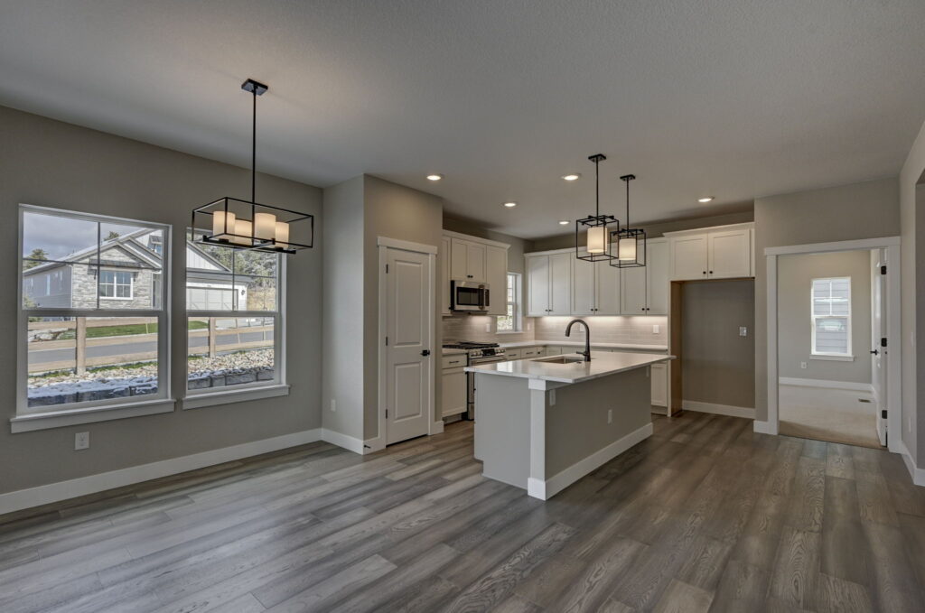 Open kitchen and dining area with center island, pendant lights, and white cabinetry.
