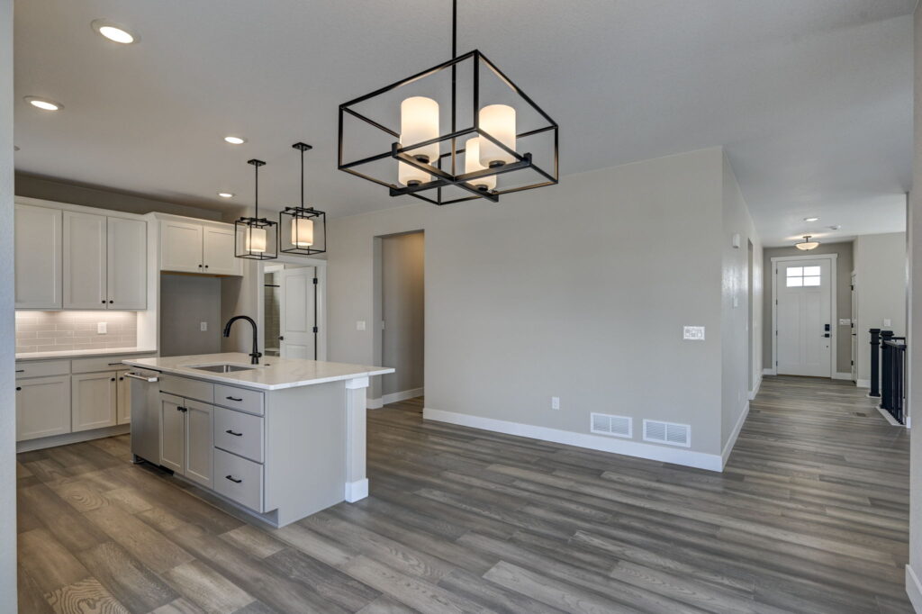 Kitchen island and dining space with square metal-framed chandelier and wood-look flooring.