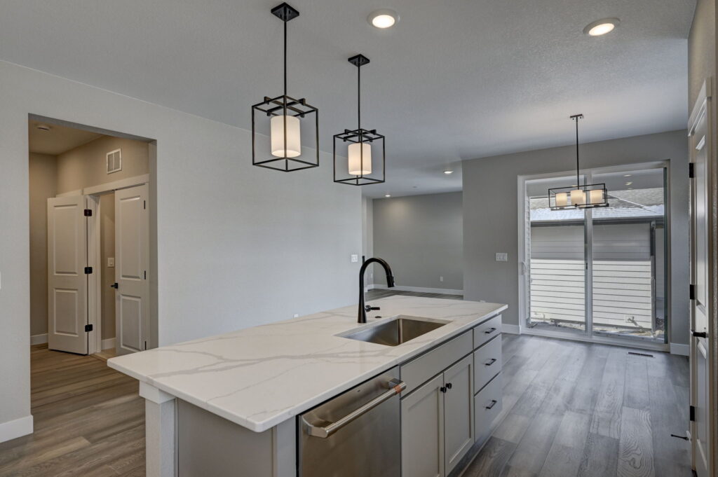 Open-plan kitchen looking toward sliding glass door with island and pendant lights.
