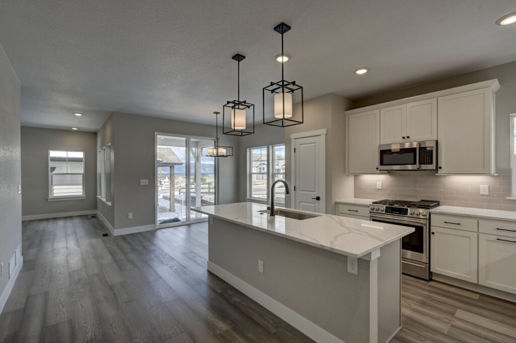 Open-concept kitchen and dining area with island, pendant lights, and wide plank flooring.