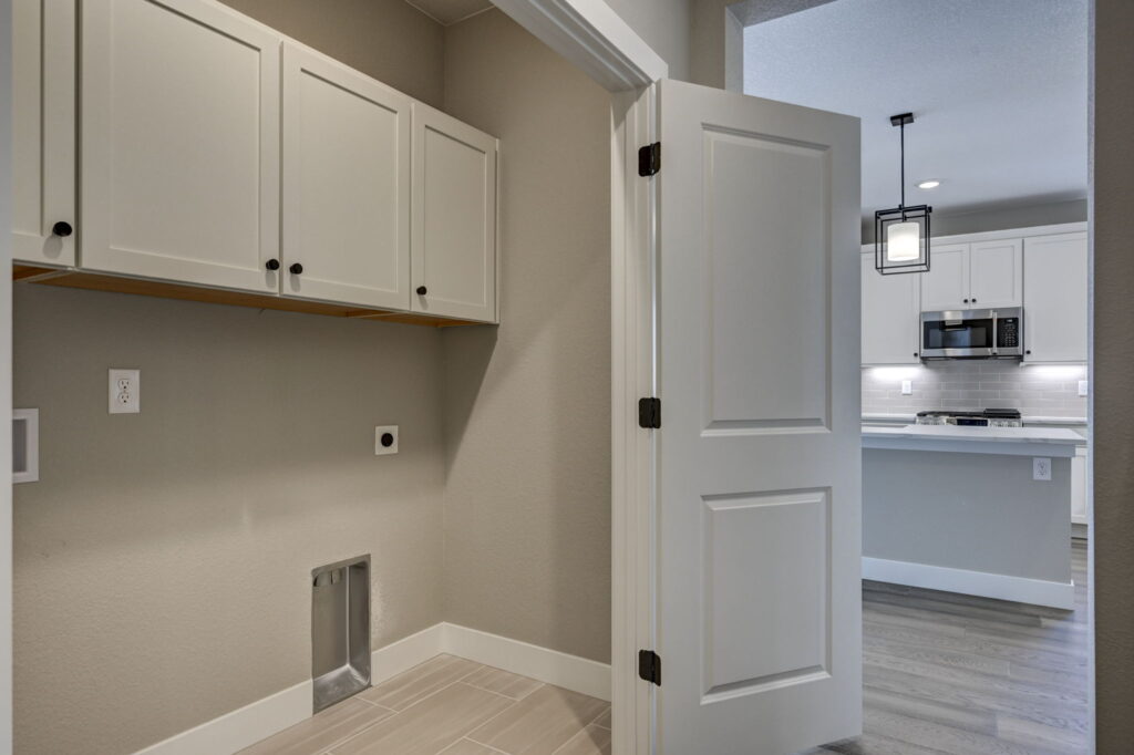 Small laundry or utility room with wall cabinets and hookups, open door to the kitchen.