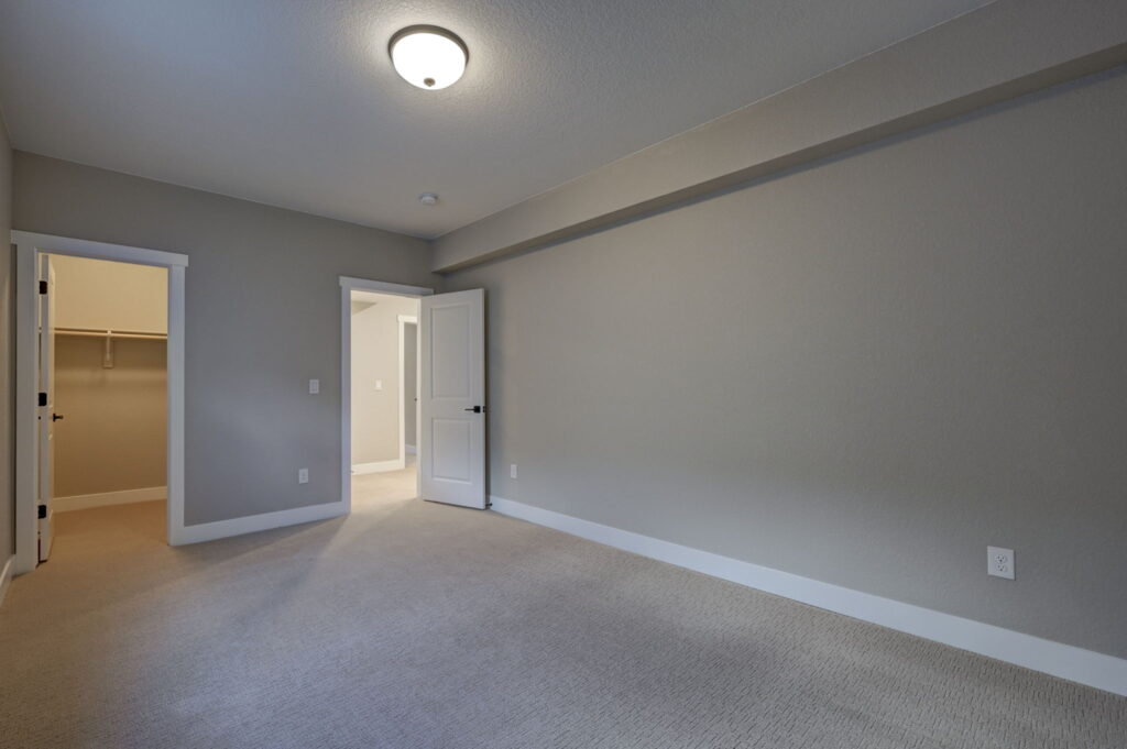 Spacious empty bedroom showing open door to hallway and a walk-in closet entry.