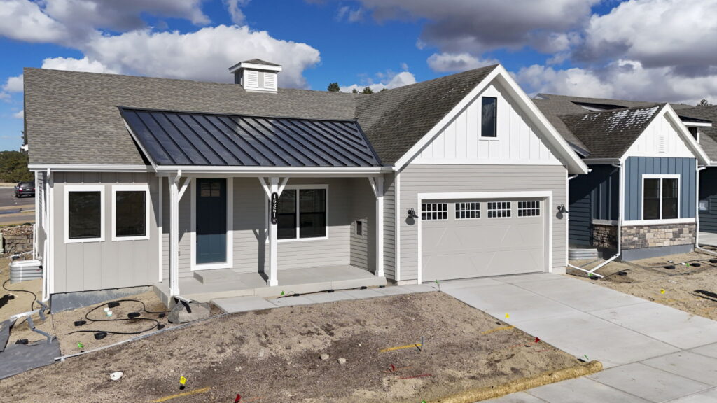 Single-story house with front porch, metal porch roof, blue entry door, and attached garage.