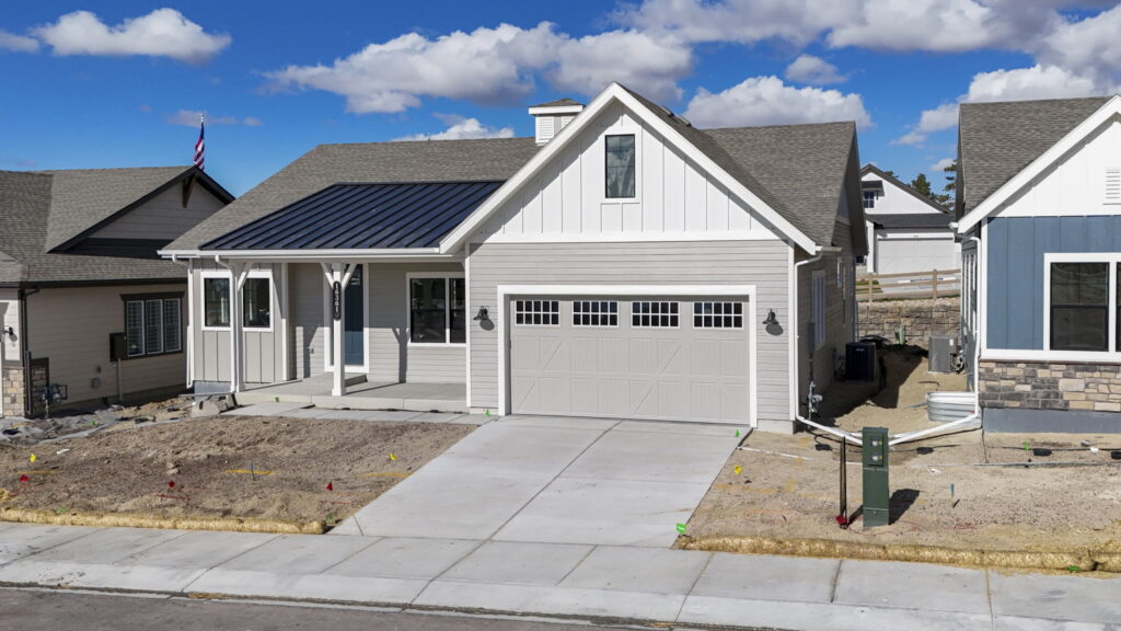 Single-story house exterior with two-car garage, concrete driveway, and partial front porch