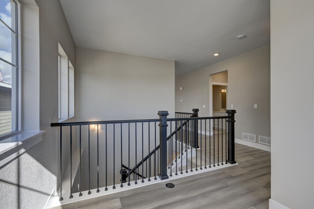 Upper landing looking over a stairwell with black metal balusters and large window light.