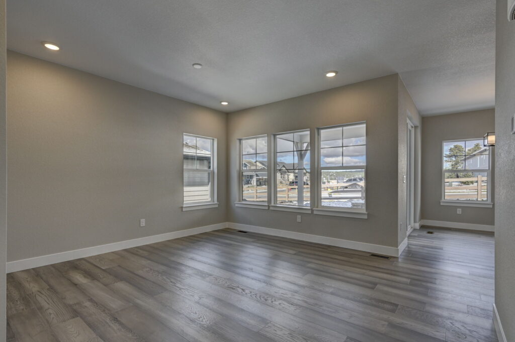 Bright living area with wood-look flooring and multiple windows along two walls.