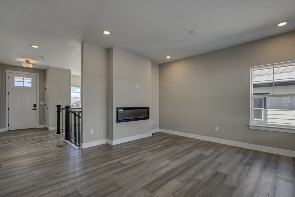 Open-plan room with electric wall fireplace, entry door visible in background.