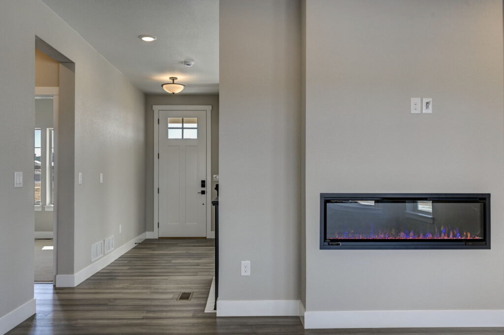 Entry hall with front door, hallway, and wall-mounted linear fireplace to the right.