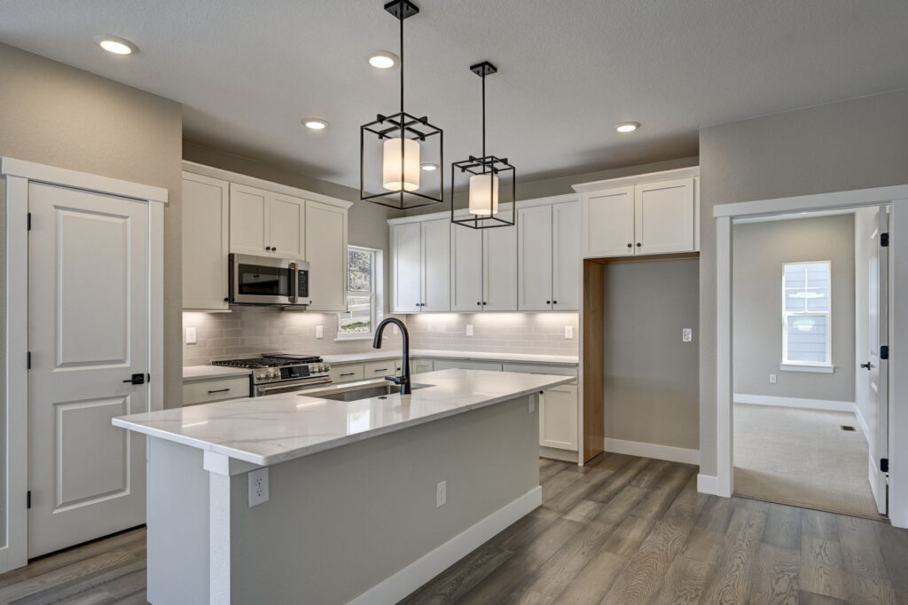 Kitchen view with large island, white cabinetry, subway tile backsplash, and pendant lights.