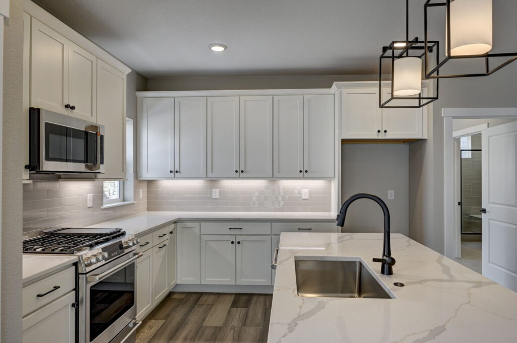 Kitchen angled view showing stove, microwave, corner cabinets, and island sink.