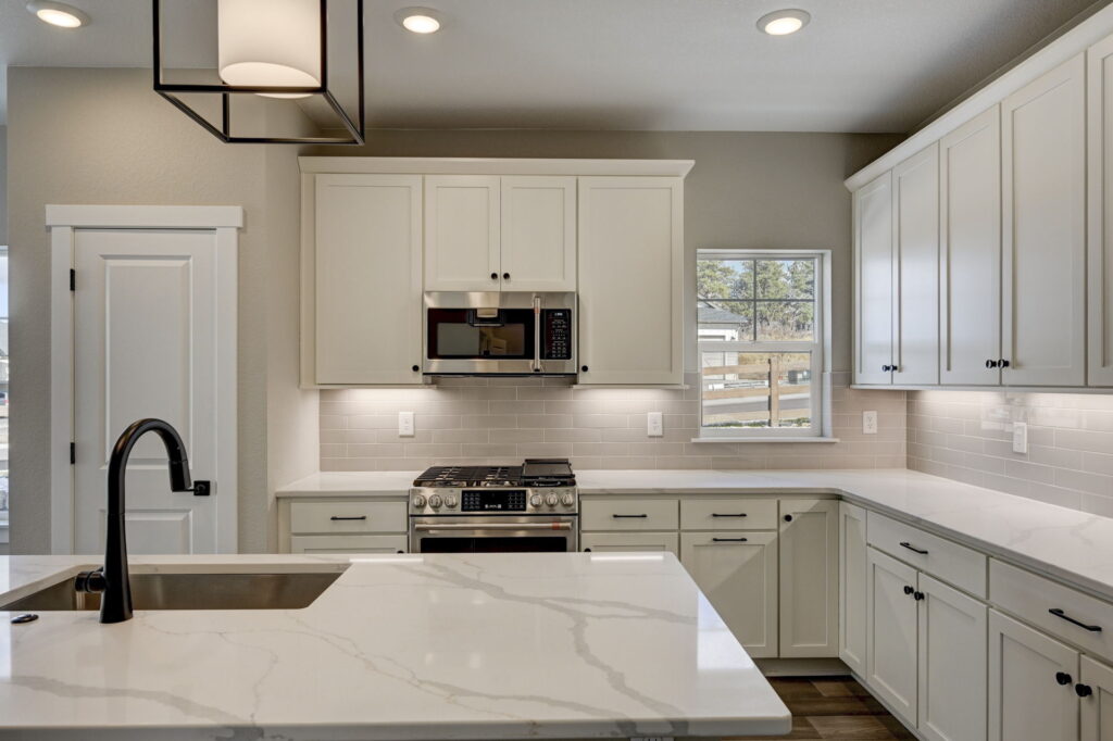 Kitchen countertop and stove with white upper cabinets and a small window above the counter.