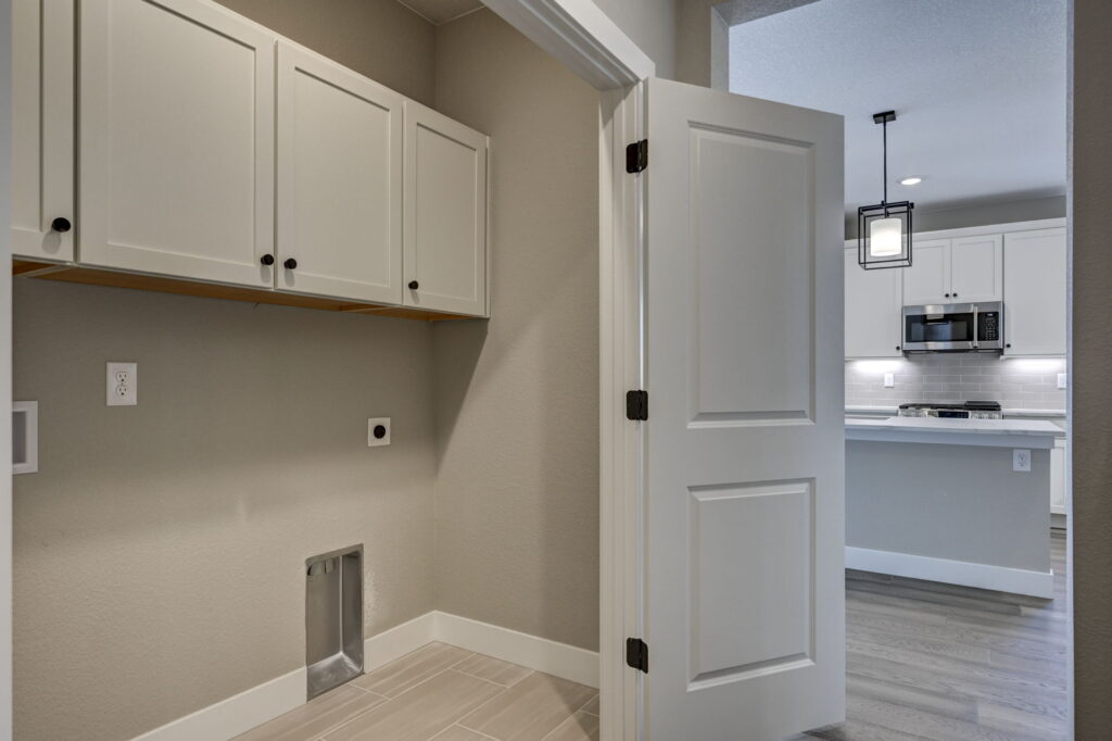 Small laundry or utility room with upper cabinets and washer/dryer hookups, open door to kitchen.