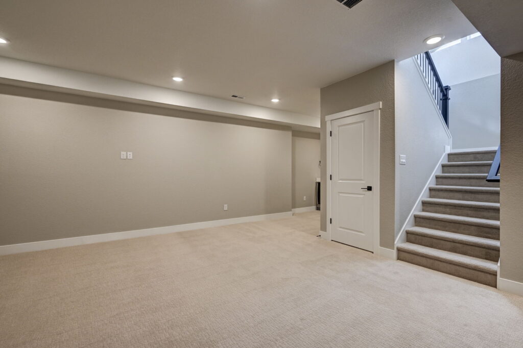 Finished basement room with beige carpet, recessed lighting, and stairs up to main level.