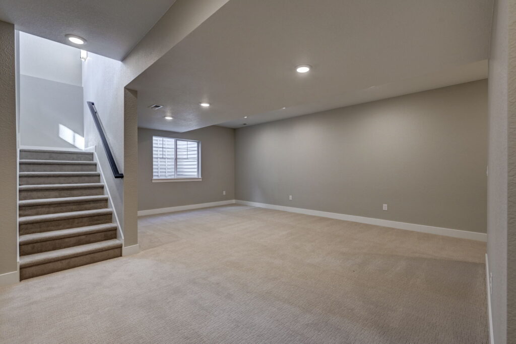 Finished basement space with carpeted stairs and a small window with shutters.