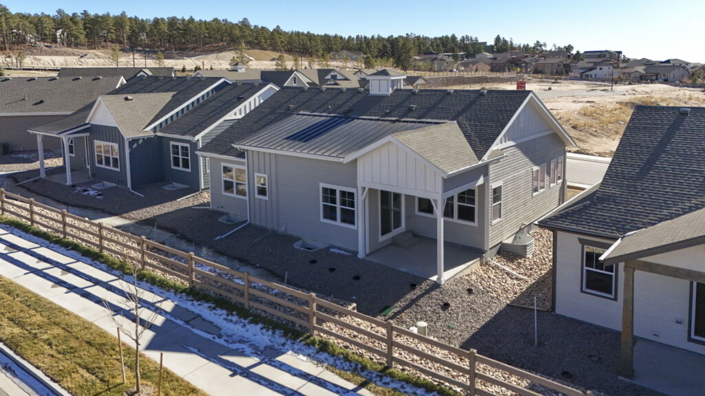 A row of single-story homes seen from above with fenced backyards and a sidewalk.