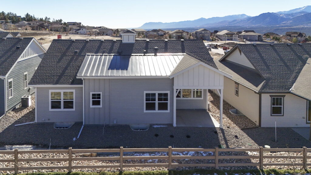 Rear elevation of a single-story house with covered patio and mountain views beyond.