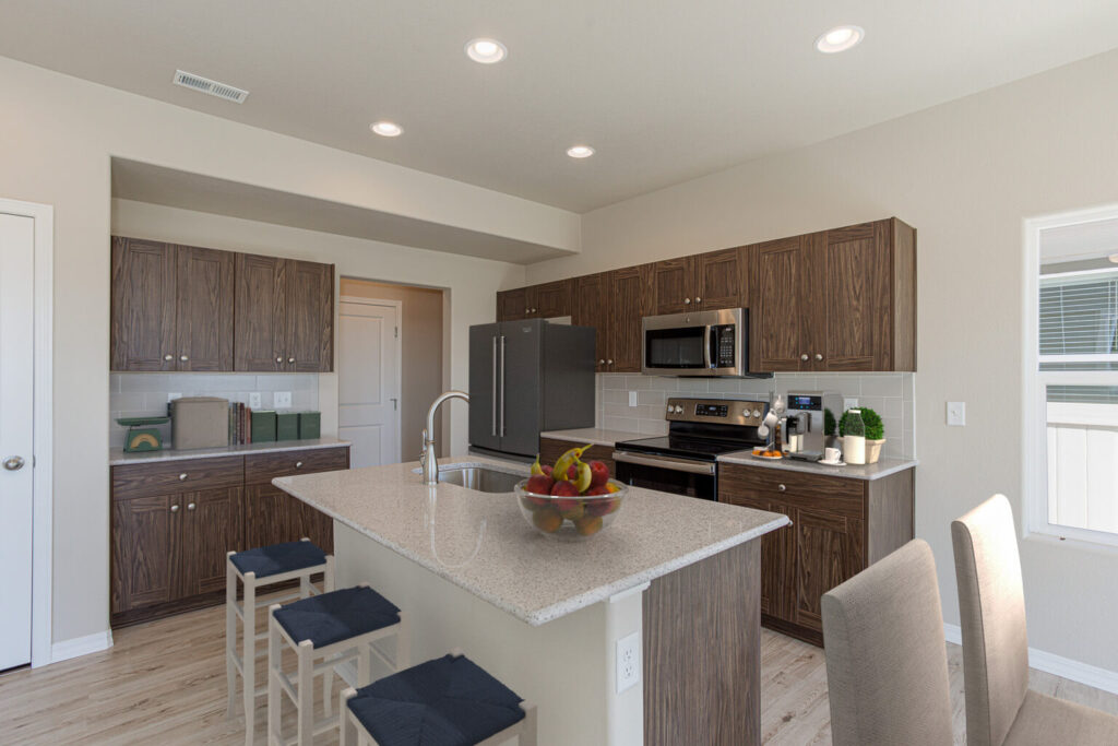 Contemporary kitchen with island, quartz countertop, wood-tone cabinets and stainless appliances.