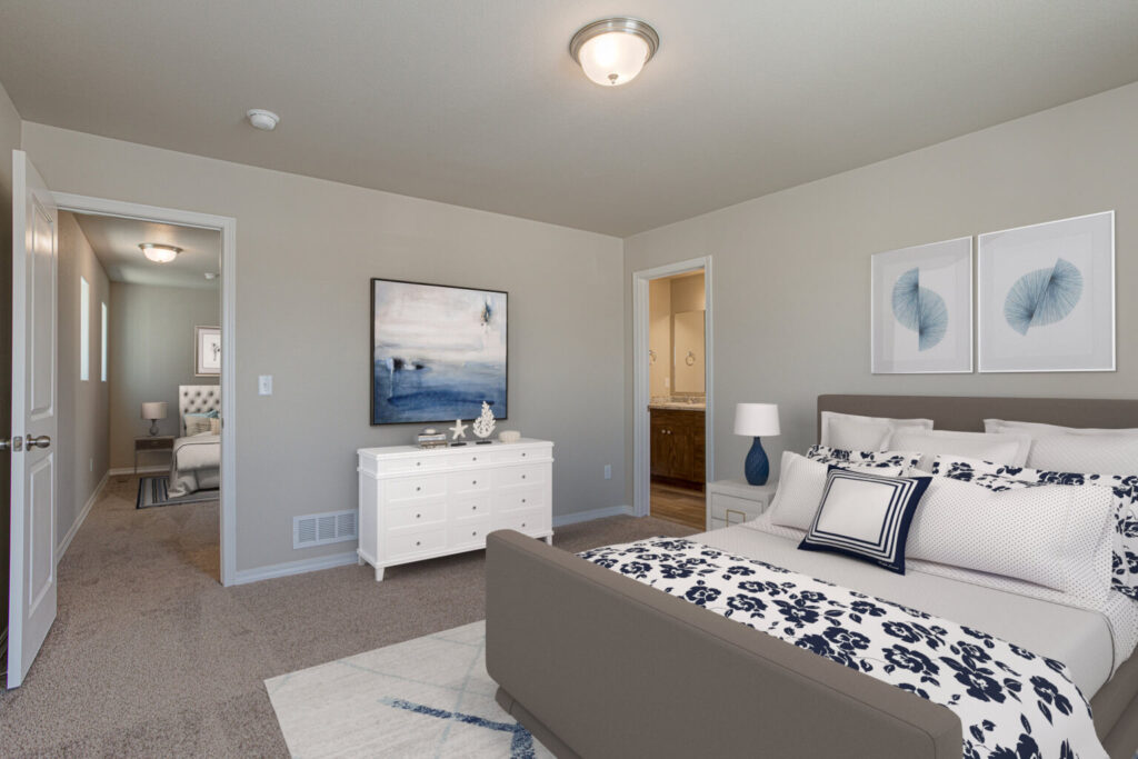 Bedroom interior highlighting bed, dresser, hallway and bathroom doorway with coastal-style artwork.