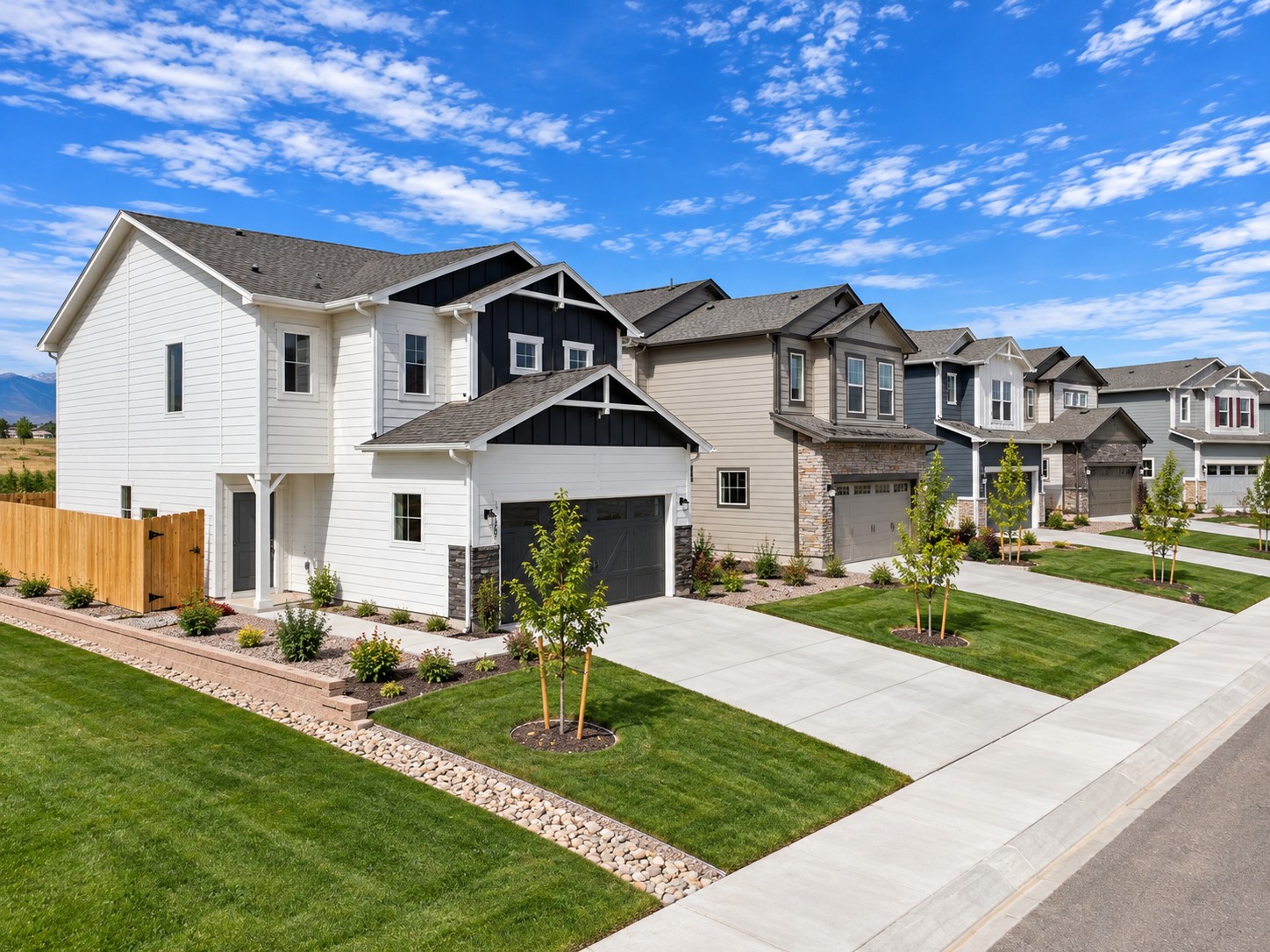 Corner view of several new two-story houses with driveways and landscaped yards.