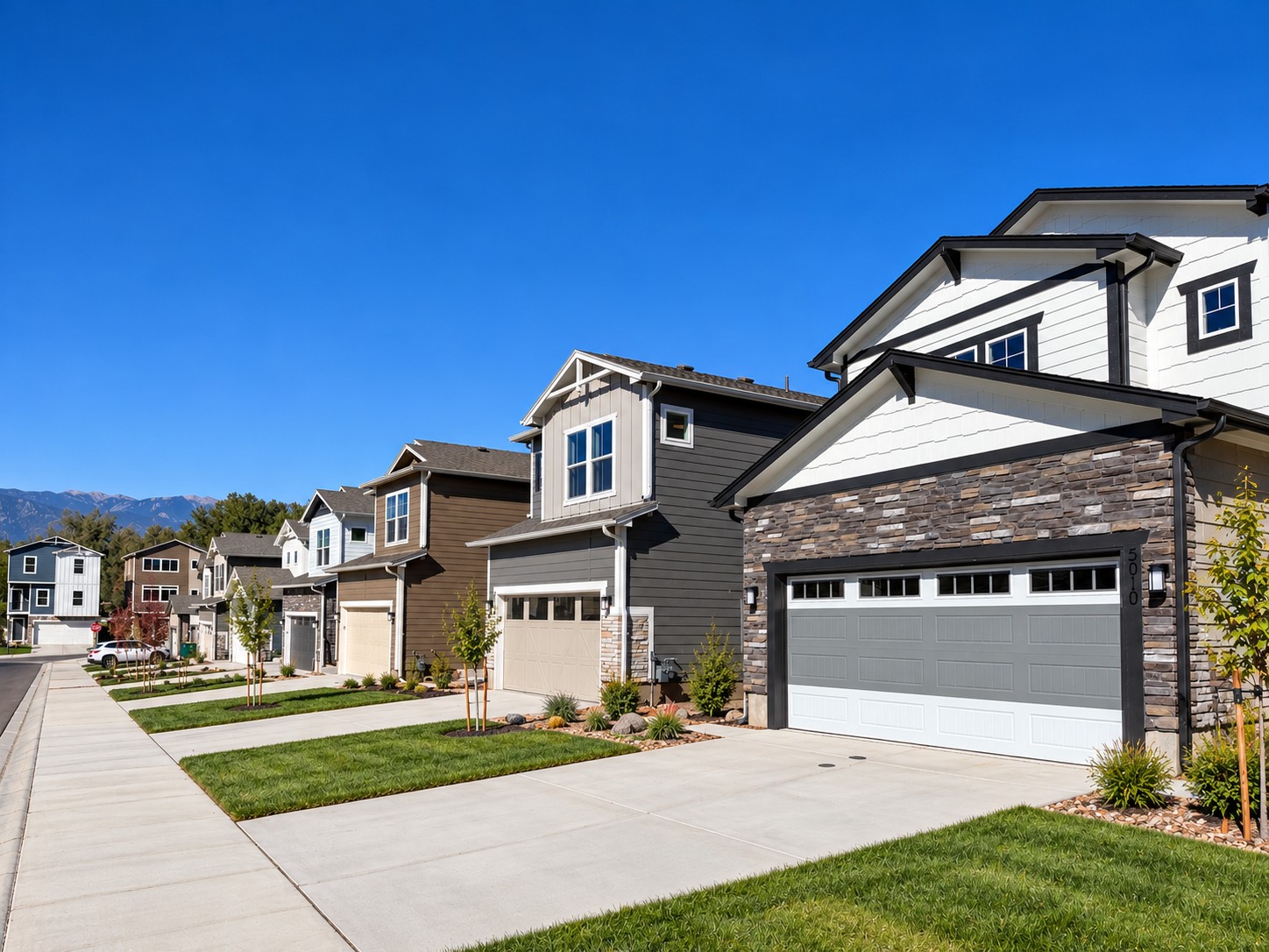 Street view of a row of modern two-story suburban houses under a clear blue sky.
