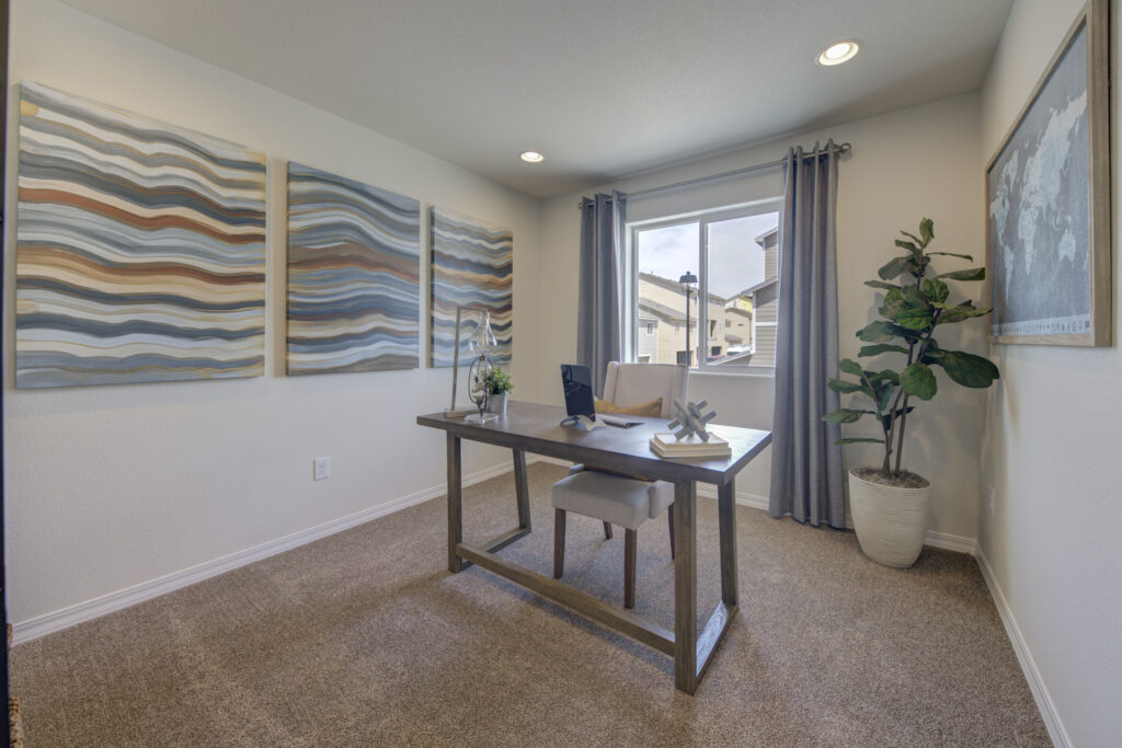 Bright office or study with desk by a window, triple abstract wall panels, and potted plant.