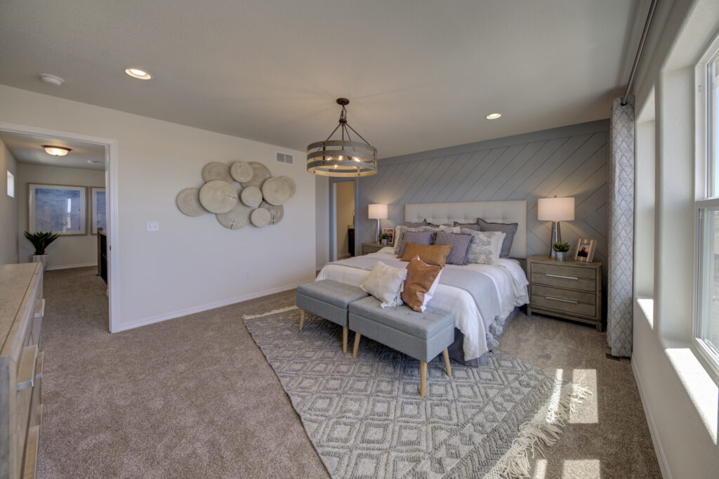 Spacious carpeted bedroom with upholstered bed, nightstands and decorative wall art.