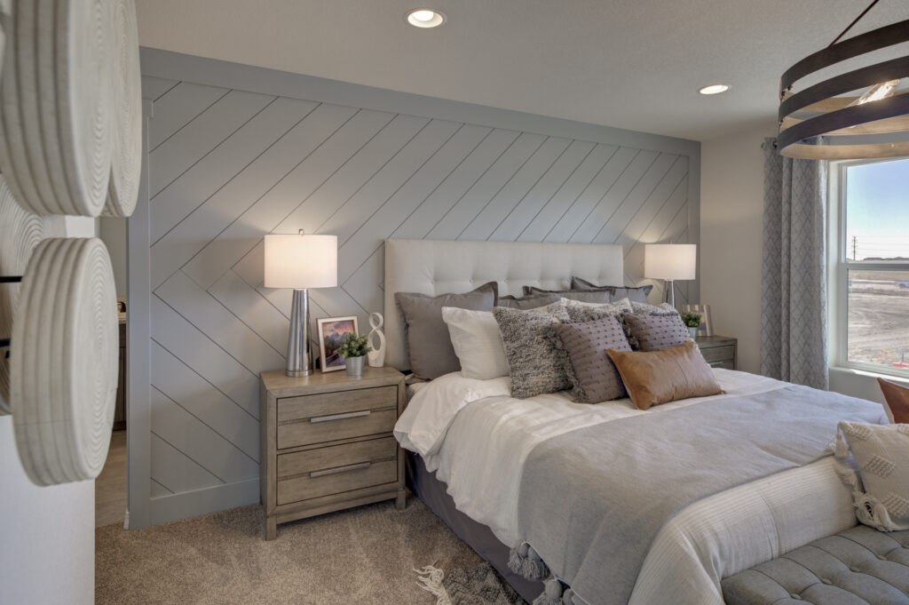Well-lit bedroom with upholstered bed, chevron-accent wall, nightstands and layered pillows.