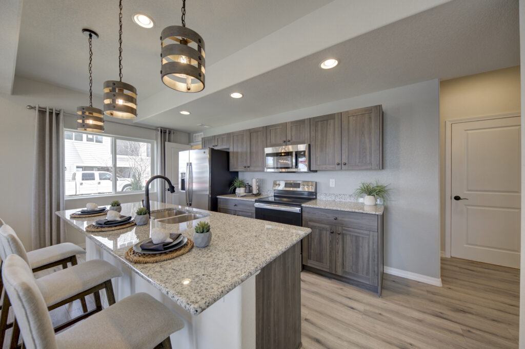 Wide-angle kitchen view highlighting island, pendant lights, and cabinets along the wall.