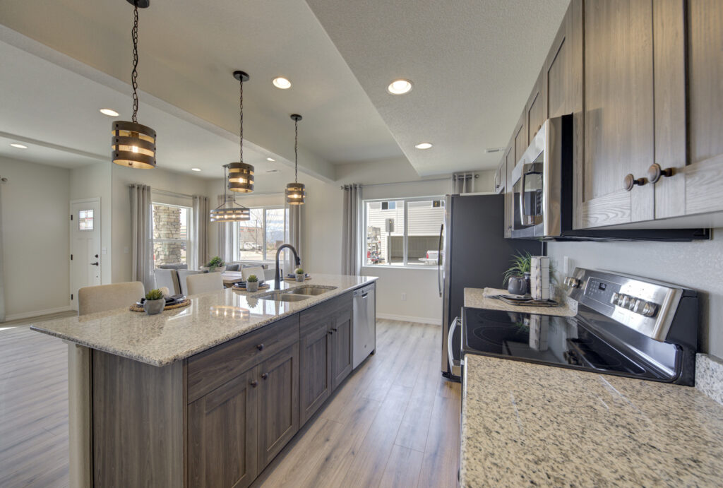 Open kitchen with large central island, pendant lights, and light wood cabinets.