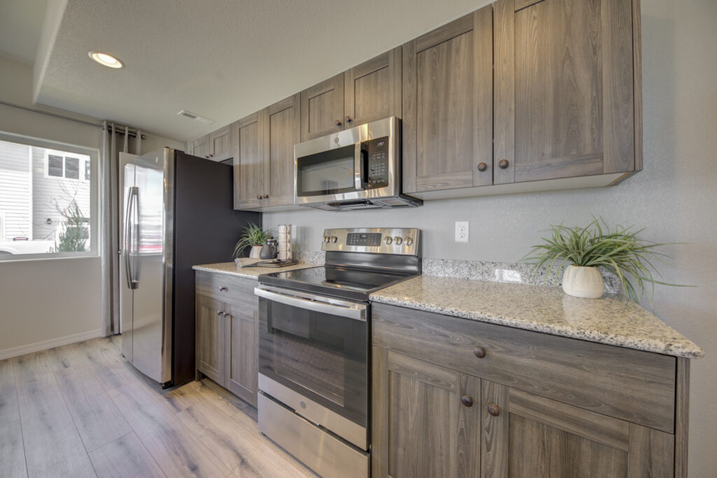 Stainless oven and microwave installed between gray wood cabinets and granite-look counters.