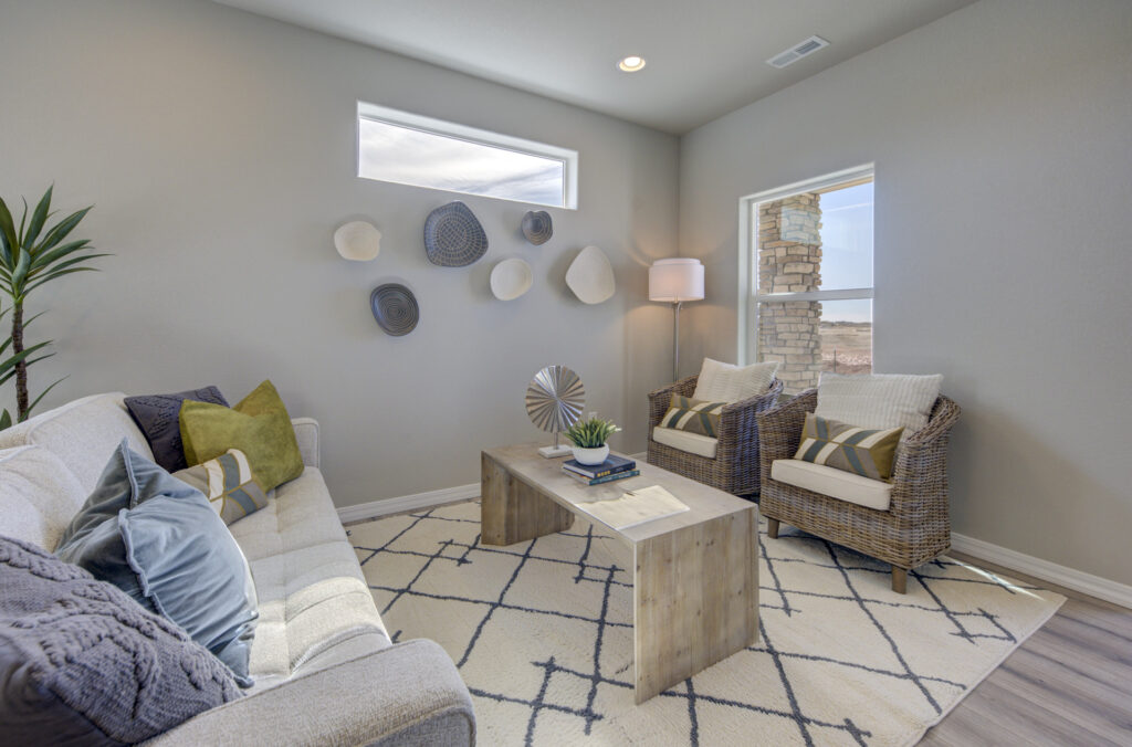 Cozy sitting nook with a sofa, patterned rug, wicker chairs and a benchlike wooden coffee table.