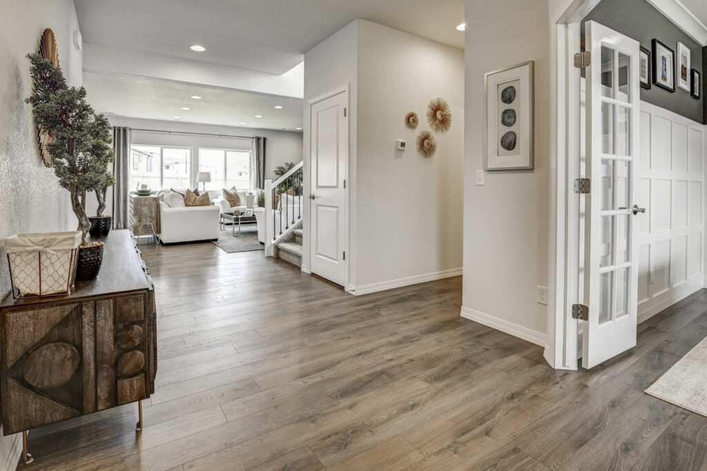 Entry area with wide plank flooring, console table, and view into living room and stairs.
