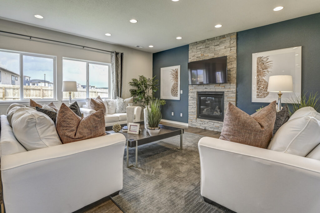 Living room centered on fireplace and TV, flanked by sofas and large windows to the left.