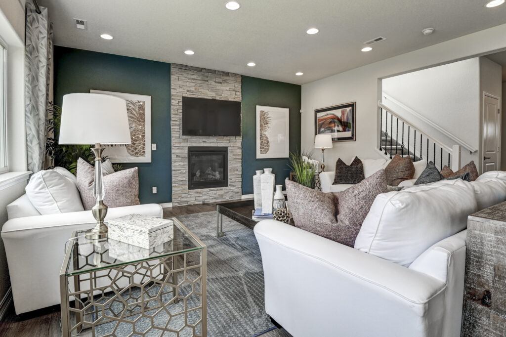 Seating area facing a stone-clad fireplace and wall-mounted TV with dark accent wall.