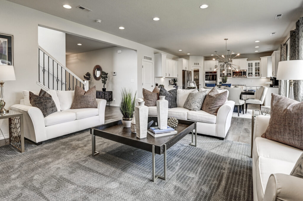 Open living room with white sofas, dark coffee table, and view into an open kitchen.