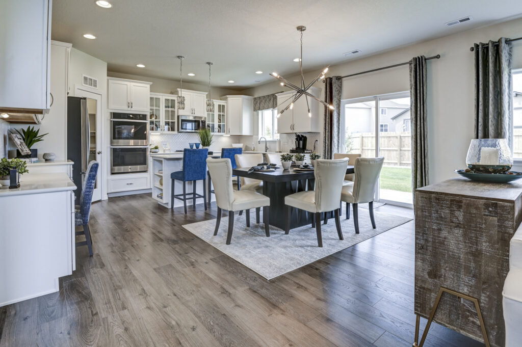 Open-plan kitchen and dining area with dark wood table, beige chairs, island, and sliding glass door.