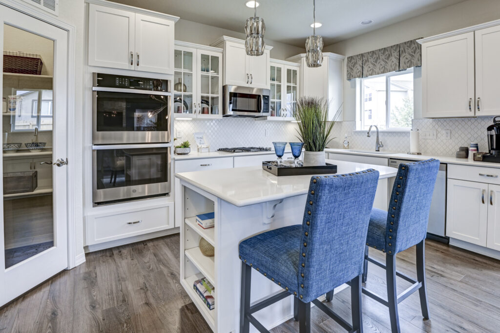 Kitchen island with two blue upholstered bar stools and built-in shelving at the end.