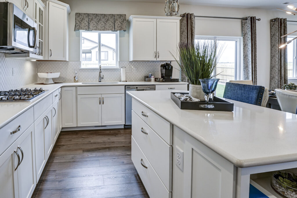 Bright modern kitchen with white cabinets, large island, and wood-look flooring.