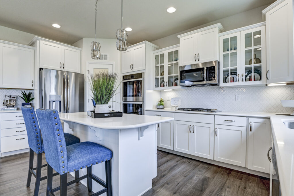 White kitchen with glass-front cabinets and blue island stools