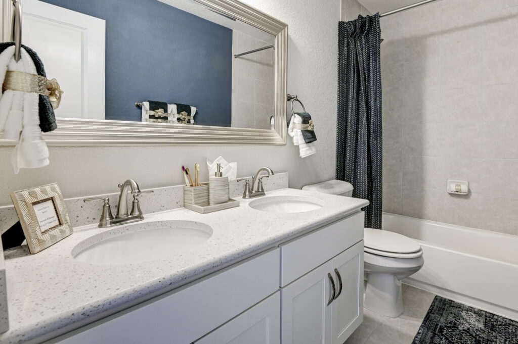 Bathroom vanity with double sinks, large mirror, and adjacent tub-shower with curtain.