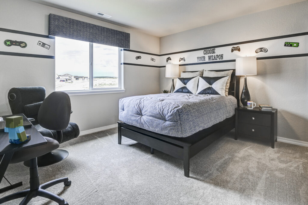 Carpeted bedroom with a bed, nightstand lamps and gaming-themed wall decals around window.