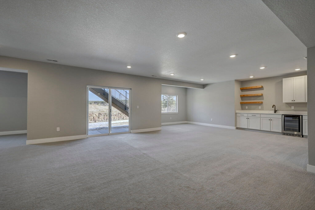 Spacious open basement with sliding glass door, wet bar, and corner window.