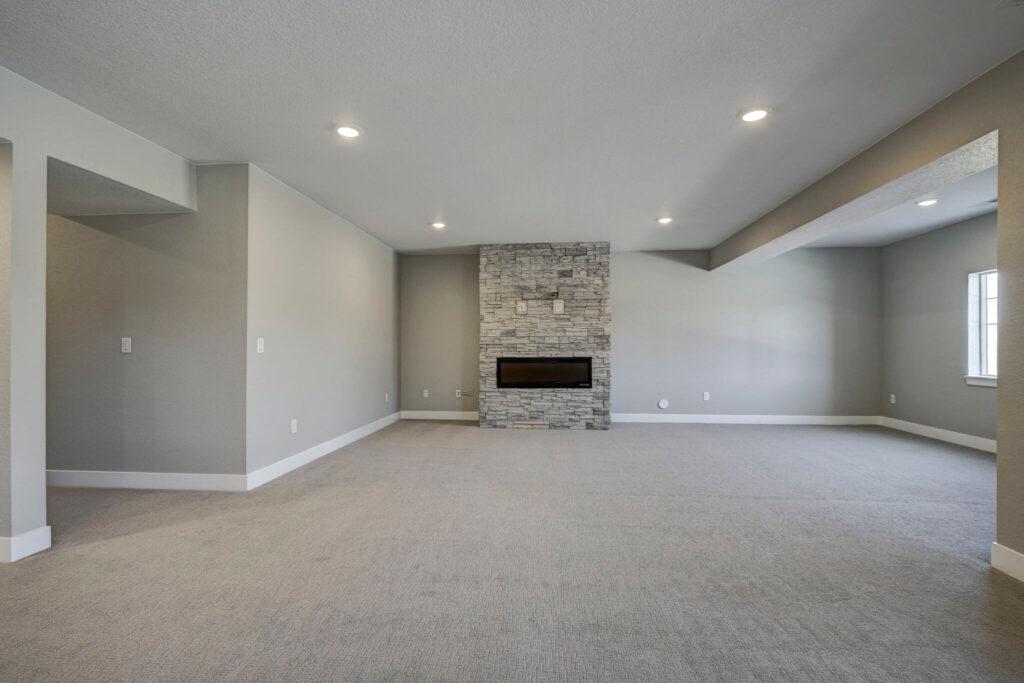 Open carpeted room focused on a modern horizontal fireplace set in a stone column.
