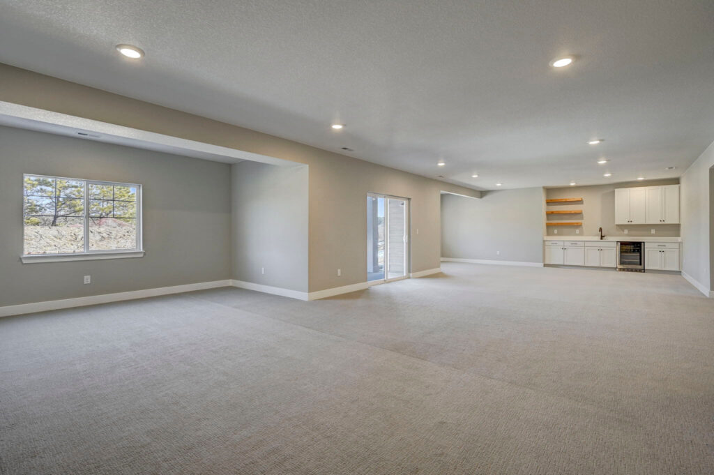 Open finished basement with wet bar, sliding glass door, and windows.