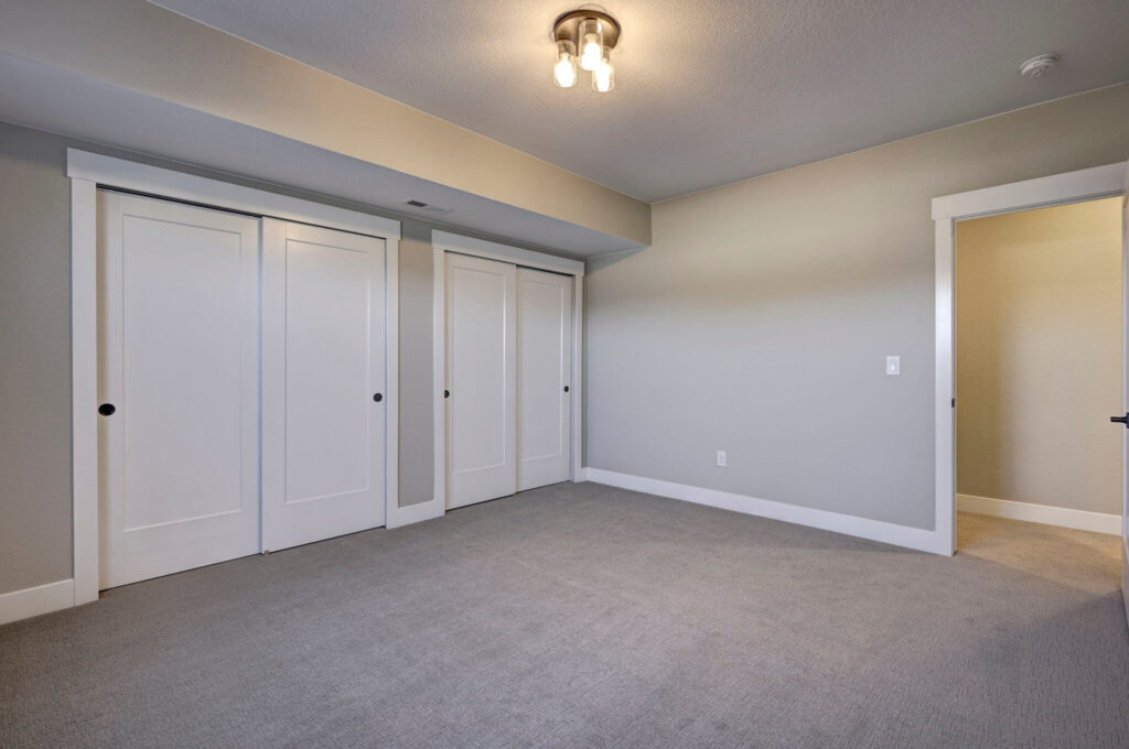 Neutral-toned empty room with three sliding closet doors and a ceiling light fixture.